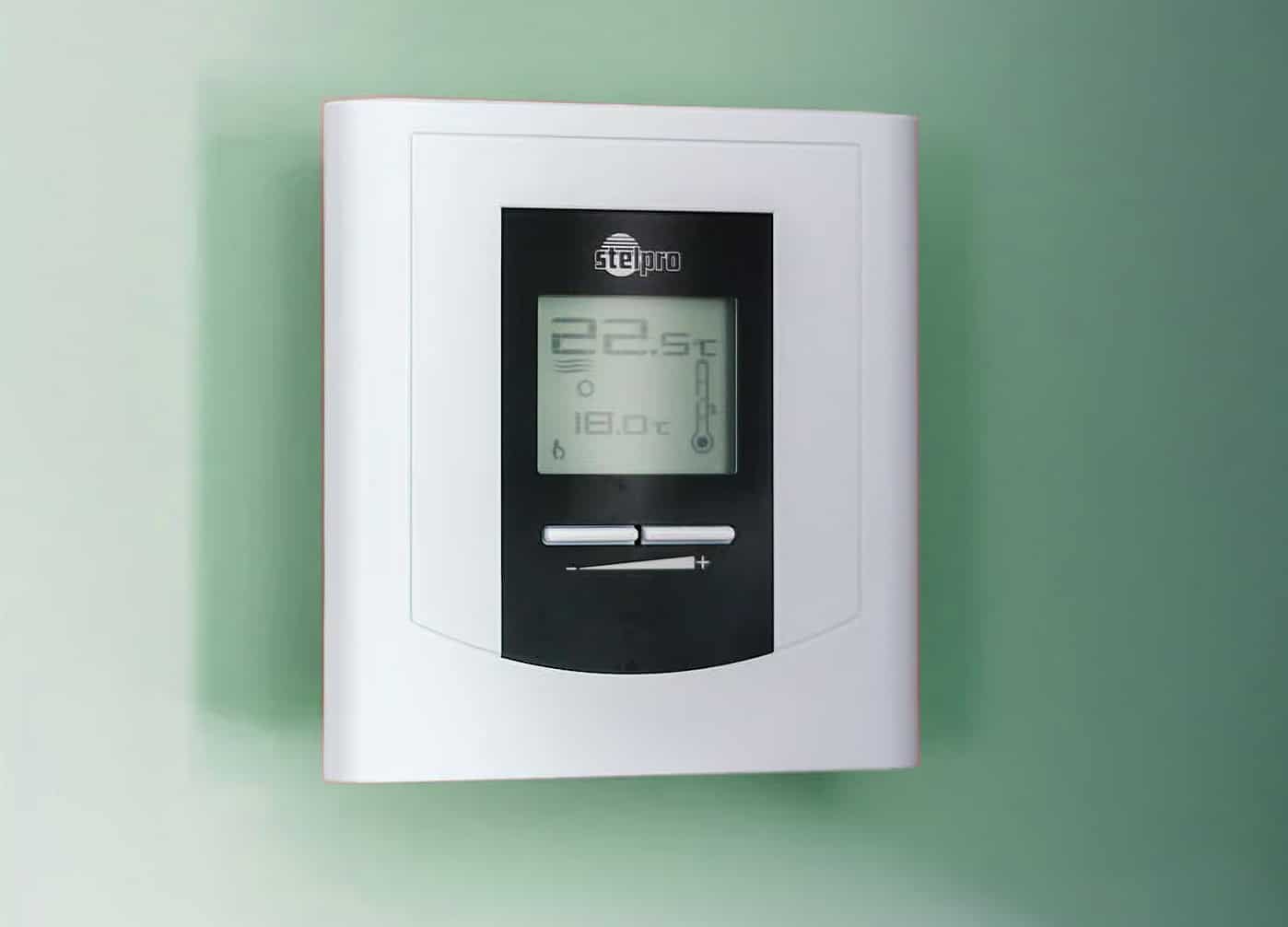 Close-up of a modern digital thermostat mounted on a wall, displaying temperature settings in Celsius.